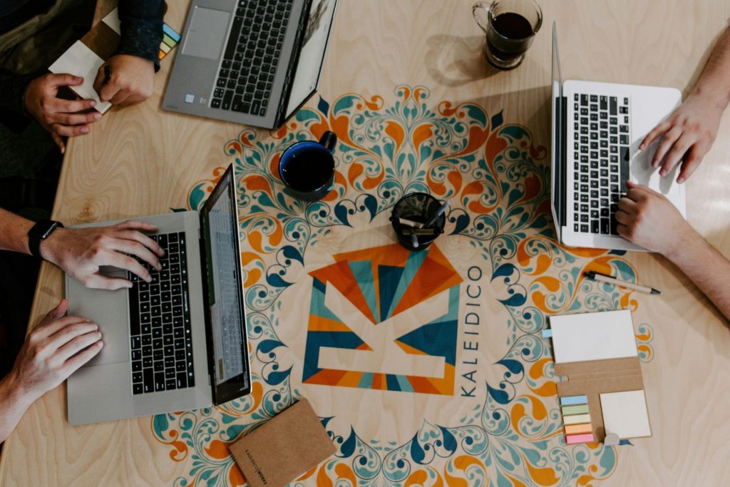 Team of individuals typing on laptops together at a desk.