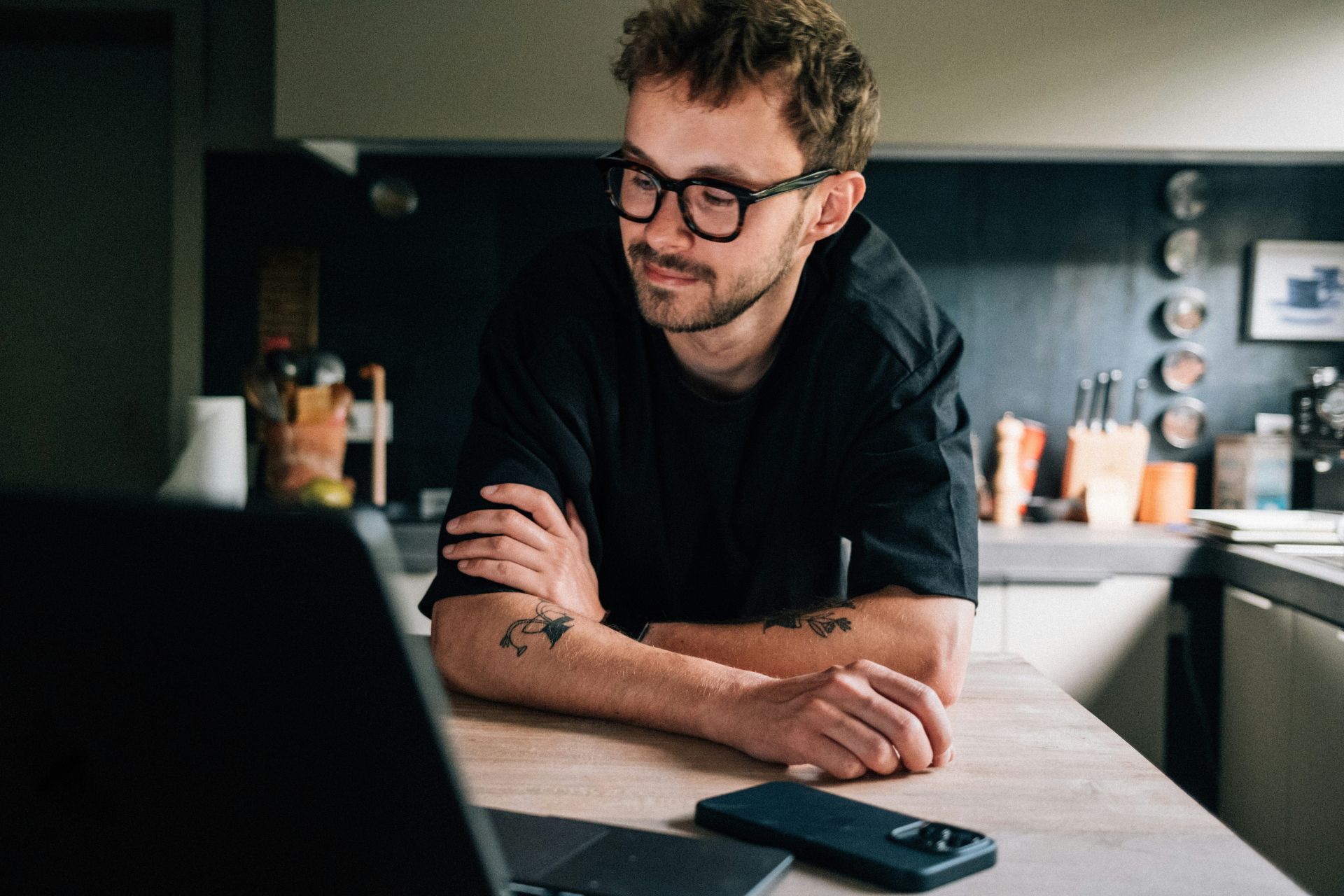 A person leaning on a counter looking at his laptop