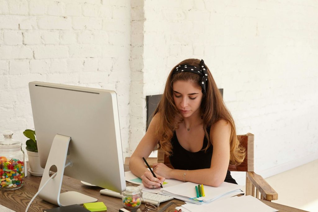 A girl who is working at her desk writing notes down for a direct mail marketing event