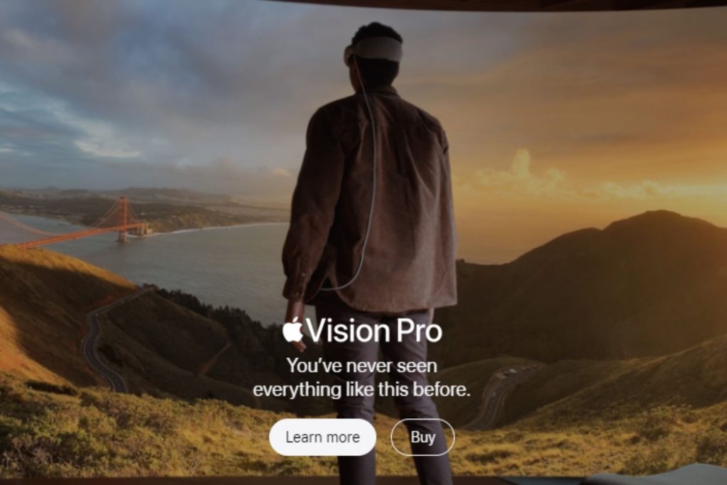 A man standing on a hilltop overlooking the Golden Gate Bridge at sunset with an advertisement for Vision Pro that reads "You've never seen everything like this before."