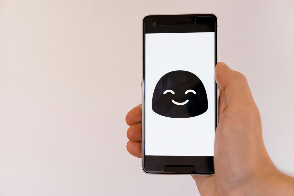 hand holding a phone with a bot icon