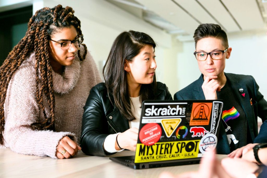 People gathered around a table with a laptop.