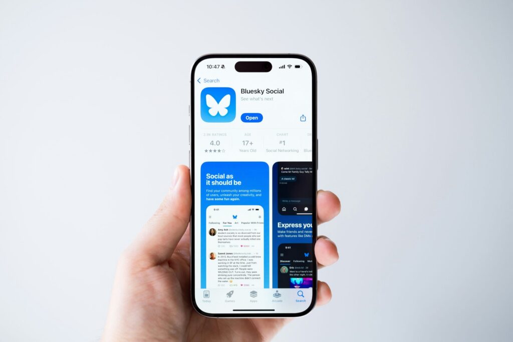 Hand holding a smartphone displaying the Bluesky social app