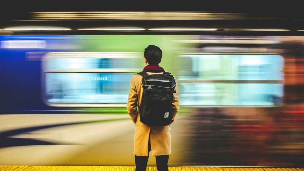man waiting in the train station with motion blur effect on moving train