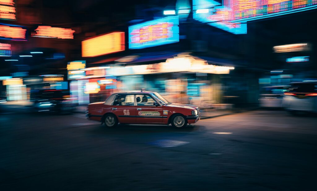 taxi driving through a blurry neon city at night
