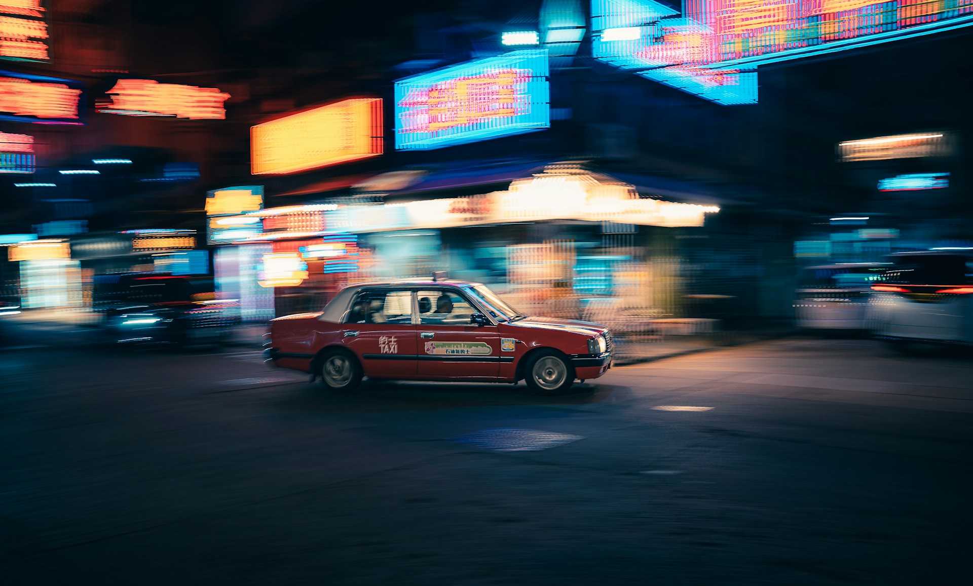 taxi driving through a blurry neon city at night