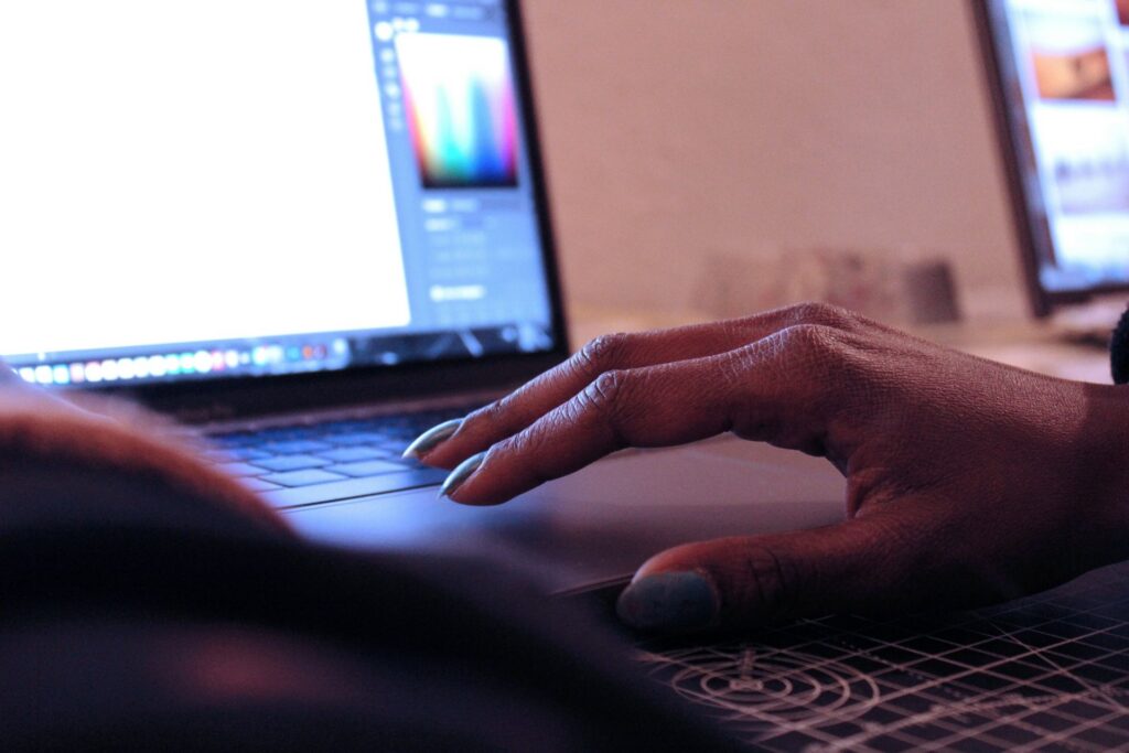 Close-up of a person using a laptop with a design interface open on the screen