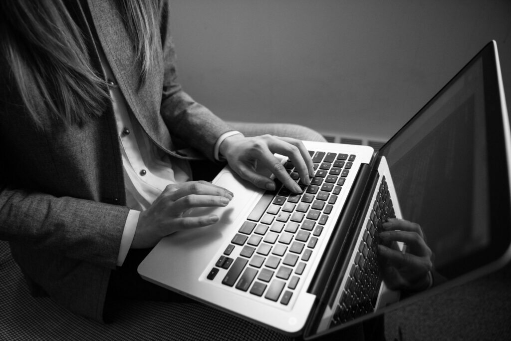 Person typing on a laptop in a black-and-white photo