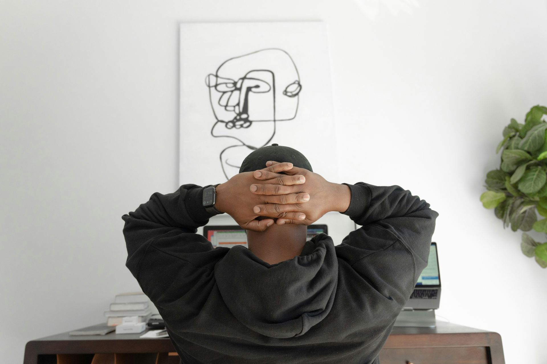 Person sitting at a desk with hands behind their head