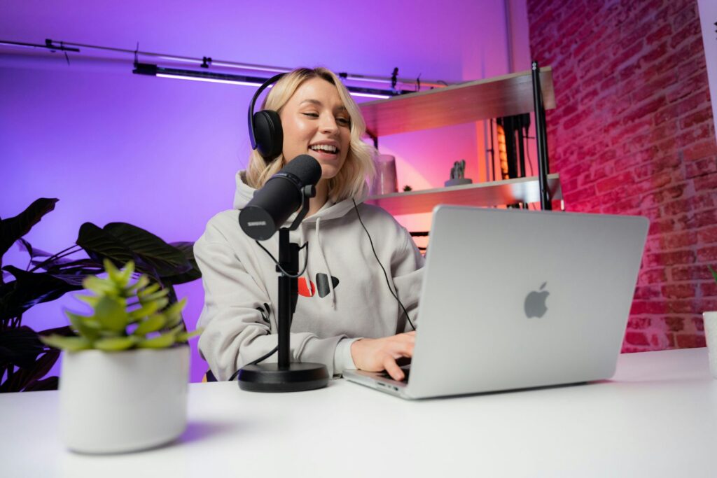 woman wearing headphones recording a podcast with a microphone and laptop