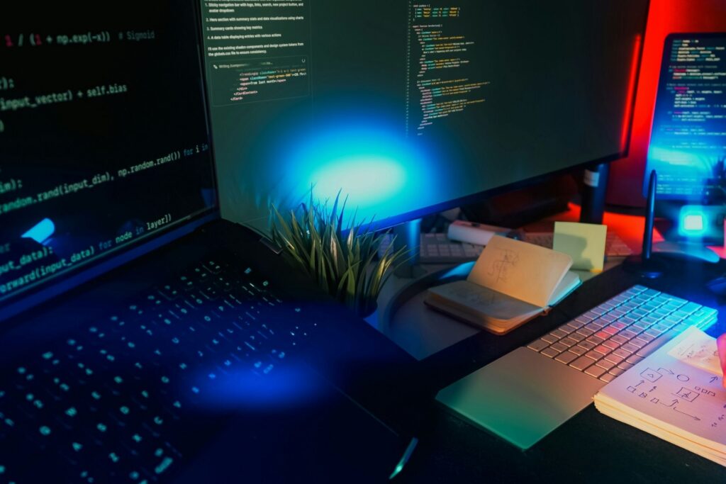 Computer monitors displaying code at a blue-lit workstation