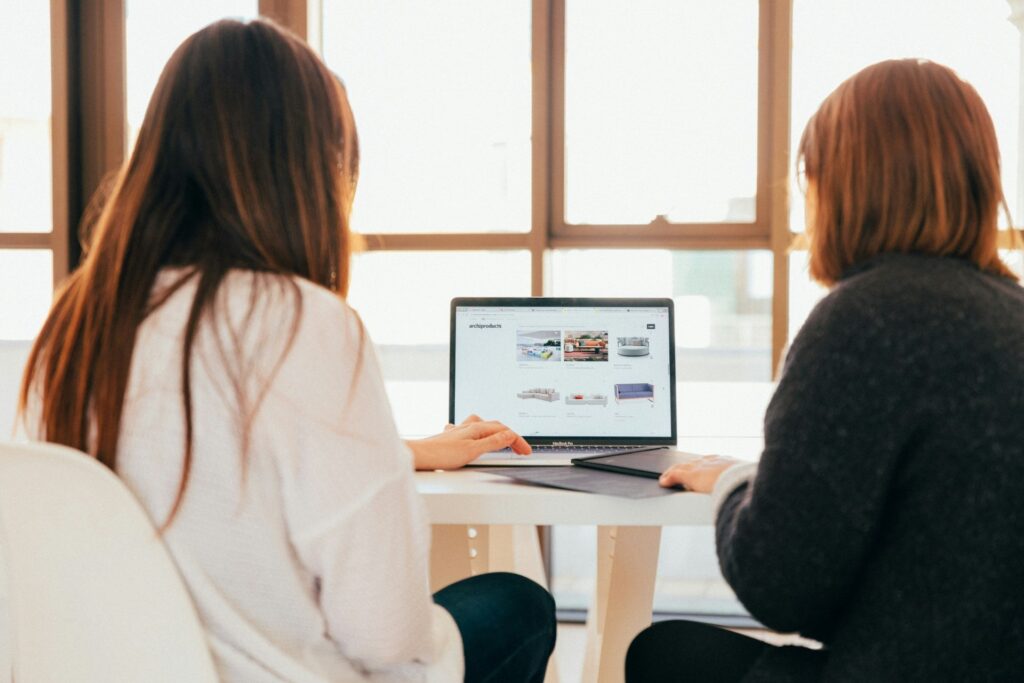 Two women looking at WordPress templates on a laptop.