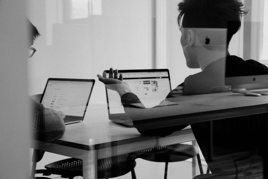 Two coworkers discussing content while working on laptops