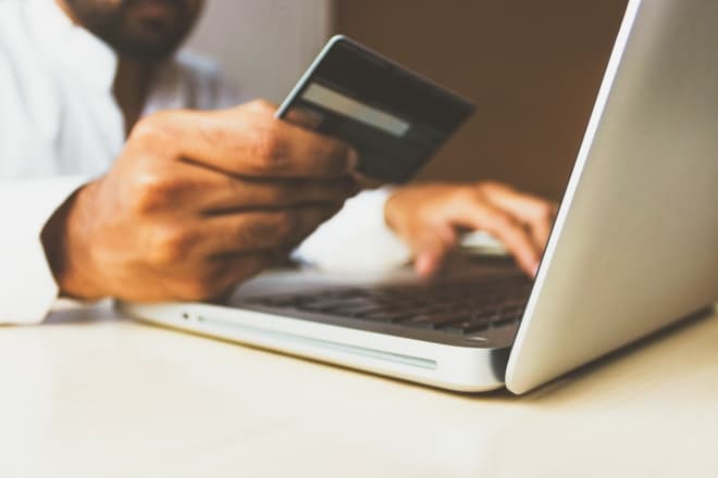 person holding credit card using computer