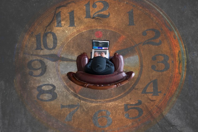 Person working on a laptop while sitting on a floor painted to look like a clock