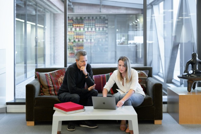 Man and woman sitting on a couch looking at a laptop