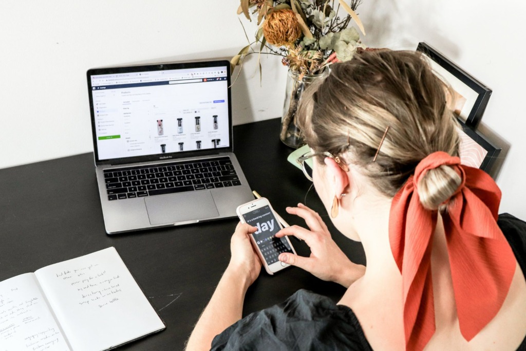 A woman sitting at a desk, using her phone.