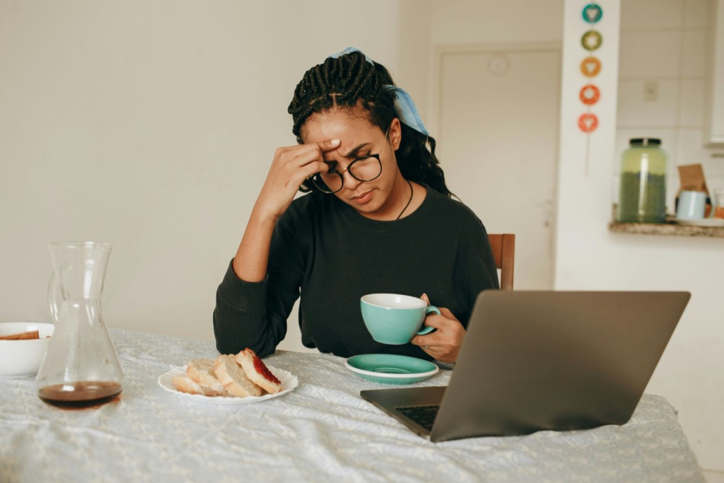 A woman working on her laptop while enjoying a cup of coffee at a table.