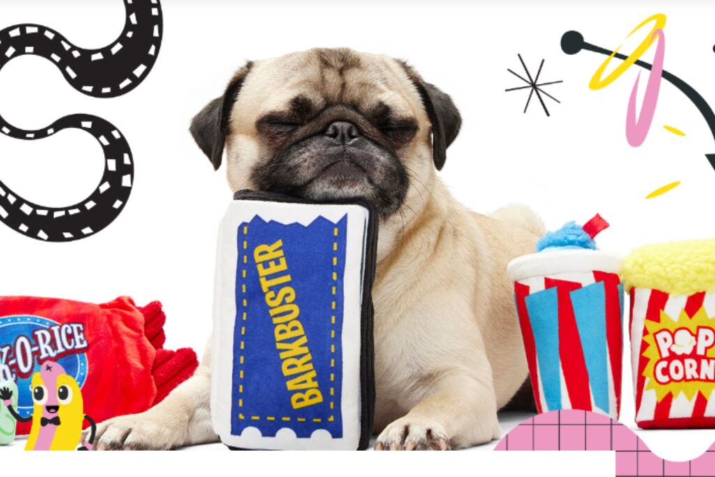 A pug sitting contentedly surrounded by colorful, movie-themed dog toys.