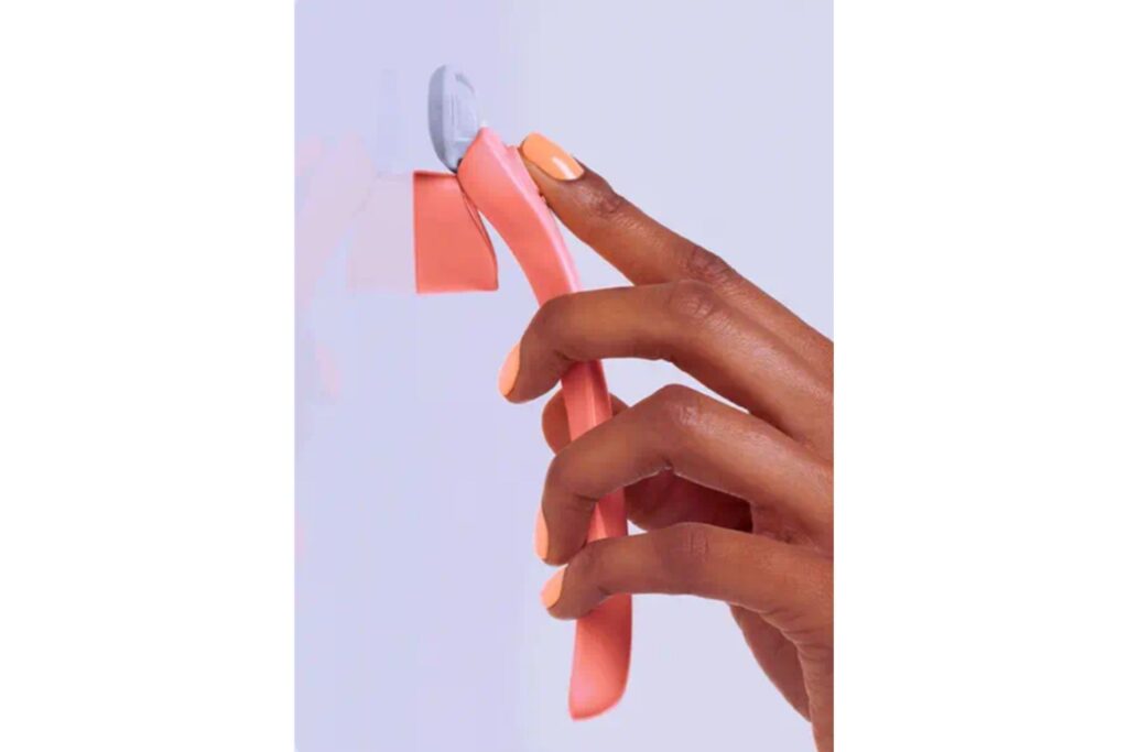 A hand holding a Billie razor against a minimalist background.