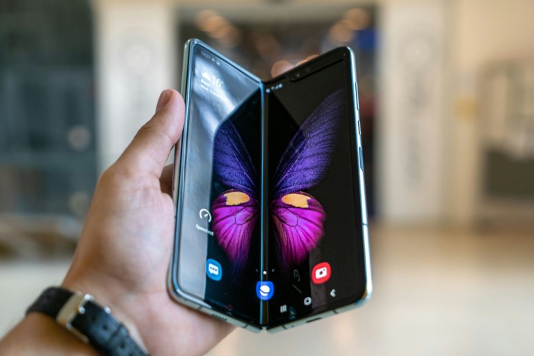 a person holding a phone folded halfway in a verticle position
