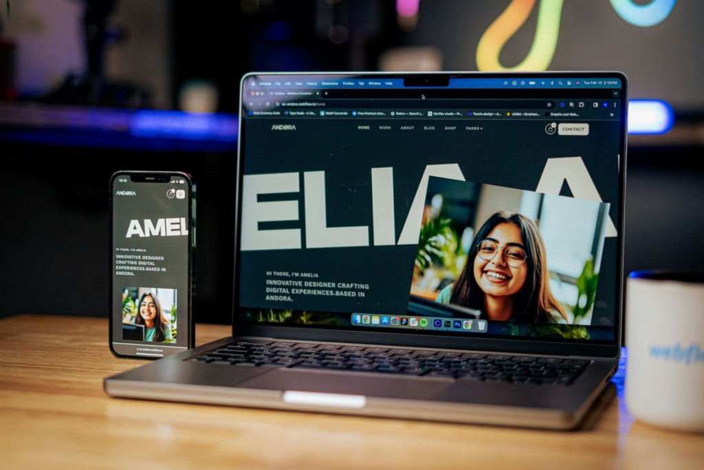 A laptop and smartphone displaying the same website portfolio sitting next to each other on a wooden table