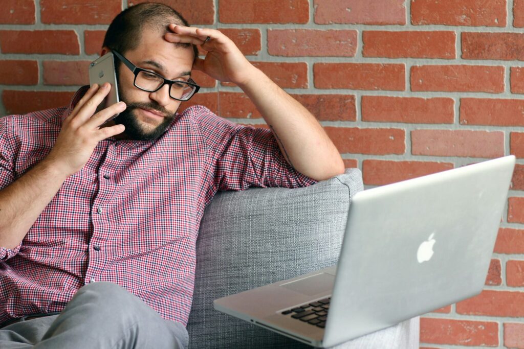 a male employee answering a phone call while looking at a laptop screen